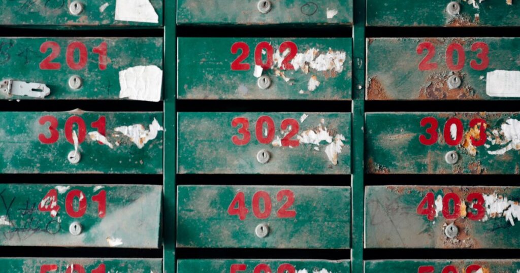 Old, rusty mailboxes with peeling paint and numbers, conveying neglect.