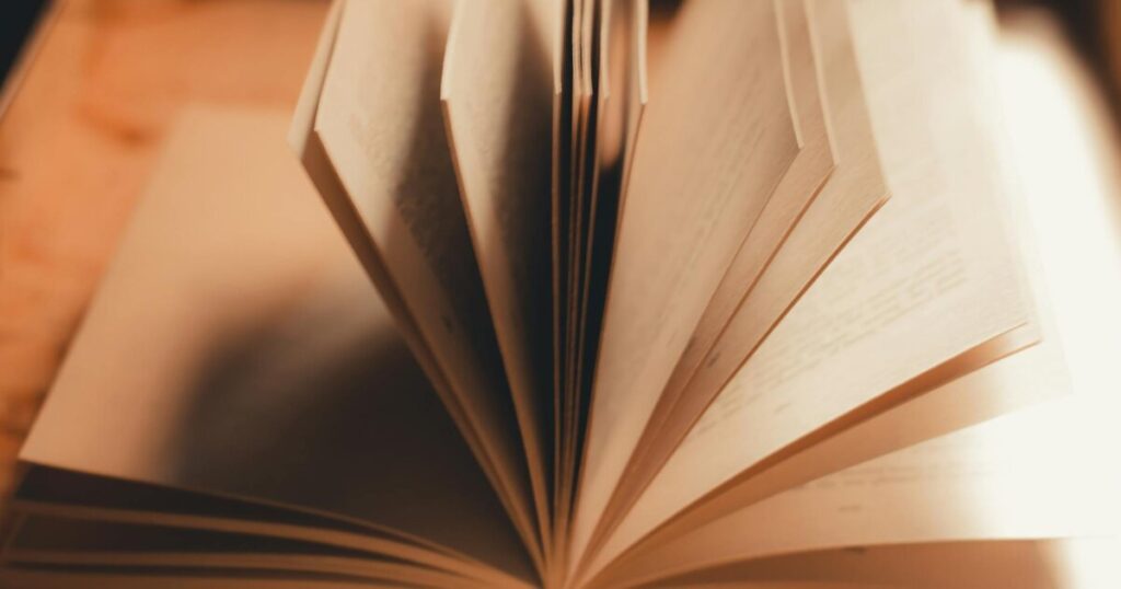 Close-up of an open book with pages turning in warm, soft light.