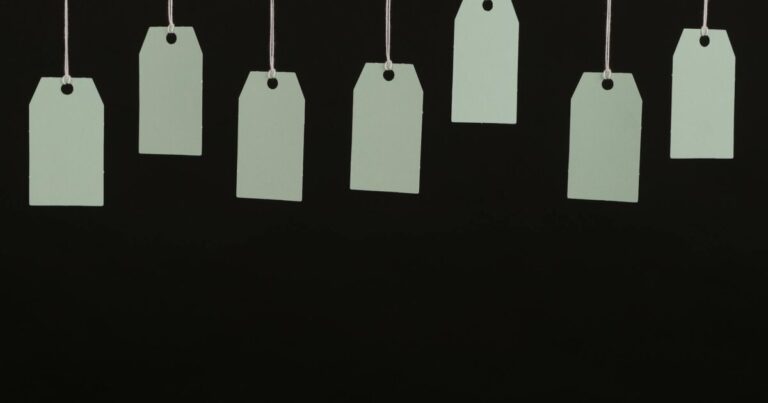 Multiple blank tags hanging on strings against a black background, ideal for designs.