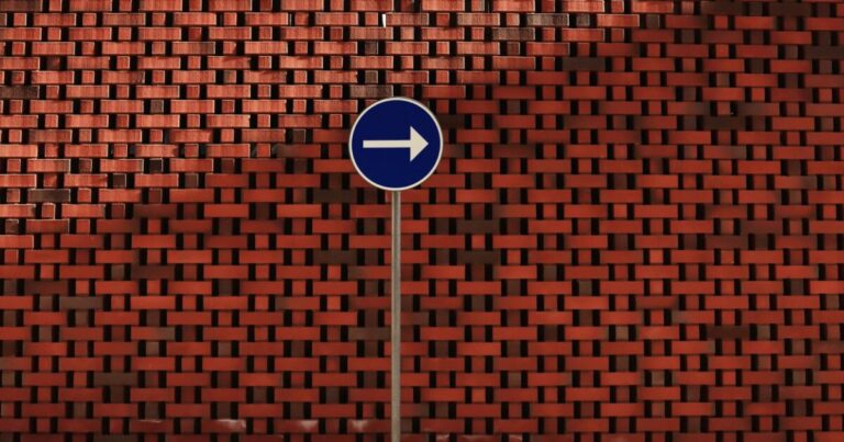 A blue right turn sign against a textured red brick wall in Norrköping, Sweden.