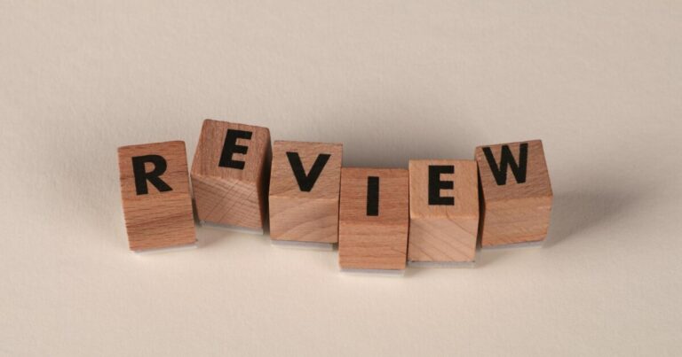 Wooden blocks with letters forming the word 'Review' on a soft pastel background.