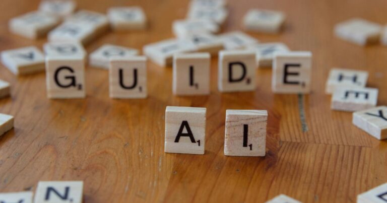 Scrabble letters spelling 'GUIDE' and 'AI' on a wooden surface, suggesting direction and technology.