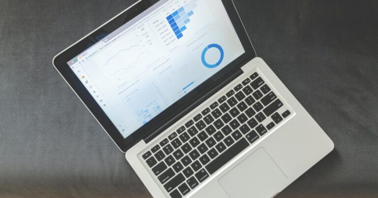 Overhead view of a laptop showing data visualizations and charts on its screen.