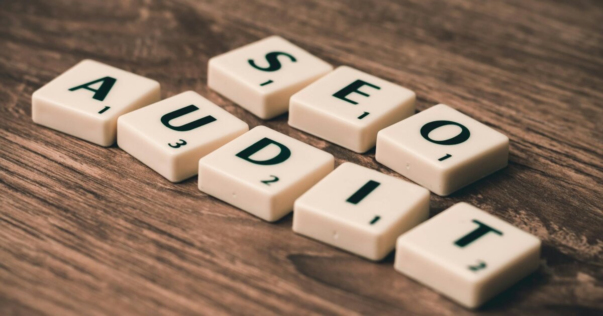 Scrabble tiles spelling SEO Audit on wooden surface, symbolizing digital marketing strategies.