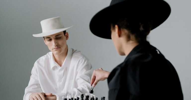 Two adults in contrasting outfits engage in a strategic chess game, showcasing style and focus.